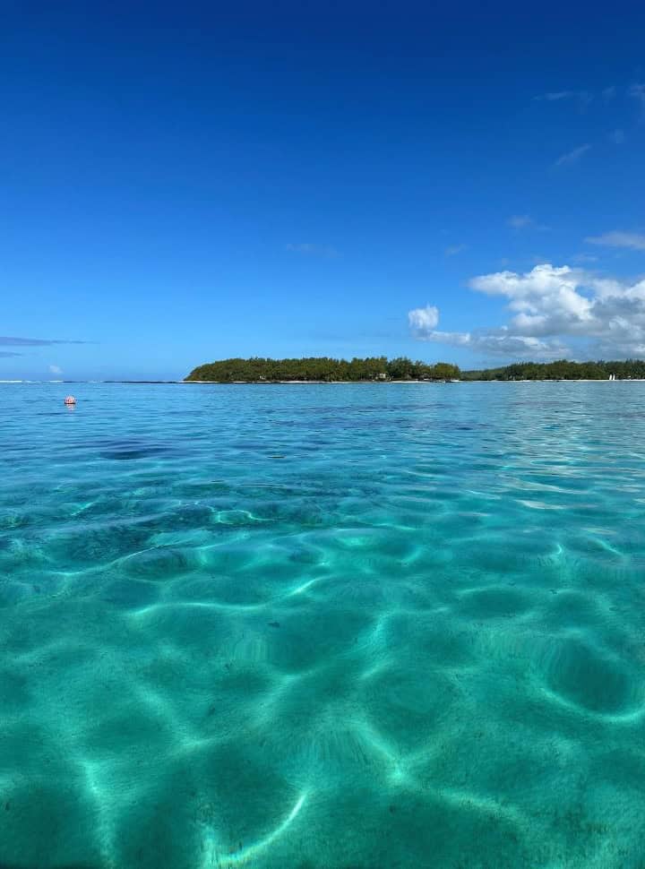 clear emerald blue water at Blue Bay Marine Park with in the back an idland, no fish visible.