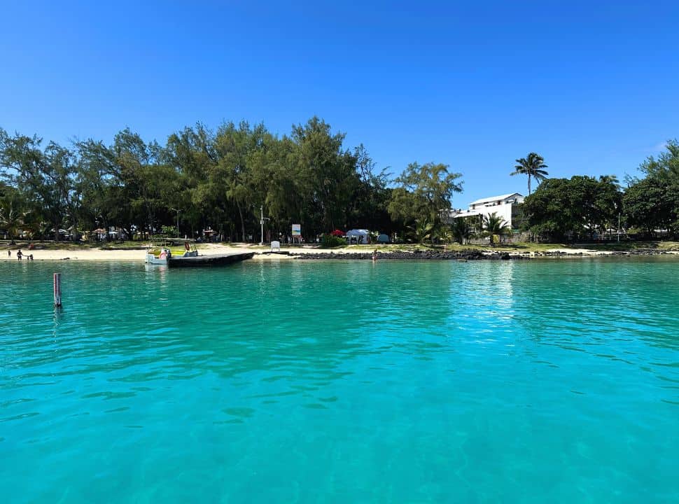 bleu bay beach taken from a boat, emerald colored crystal clear water with a boat at the waterfront. 