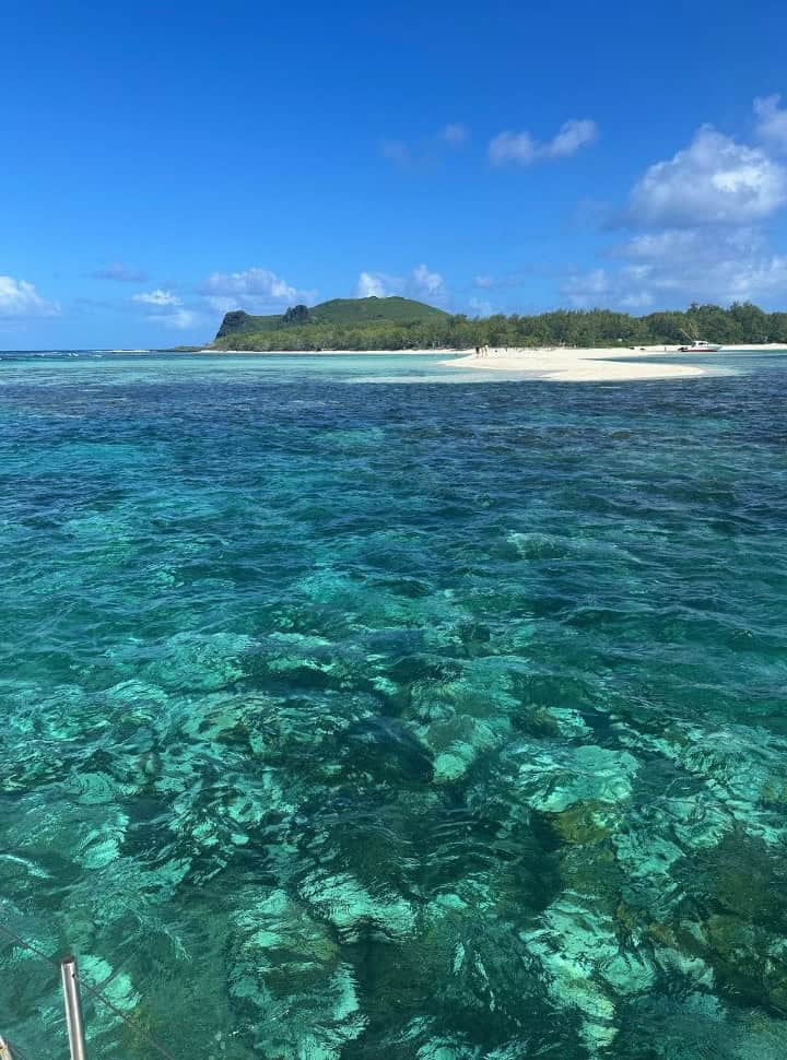 tropical island north of Mauritius with super white sand, green vegetation and a hill, surrounded by amazingly colored water in all shades of green, blue and turquoise. 