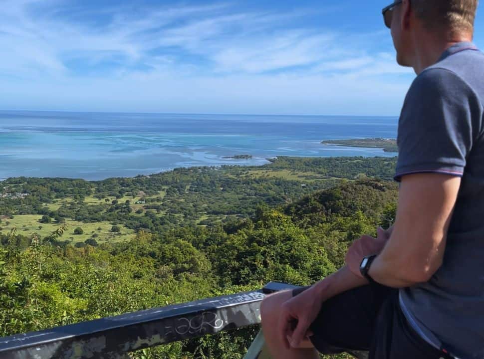 man admiring the view from the mountain top of the green valley and bleu ocean in Mauritius