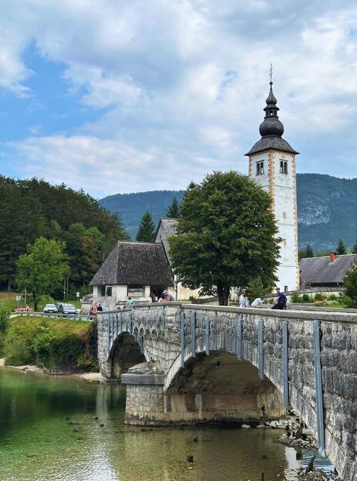 beautiful traditional church and bridge at the crystal clear lake of Lake Bohinj Slovenia