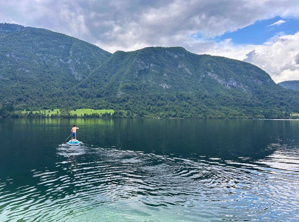 boy on a stand up paddle board in the middle of the calm lake Bohinj