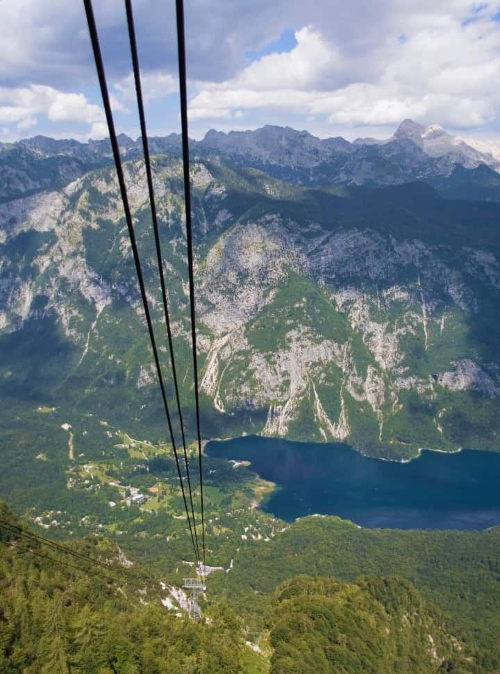 stunning view from a cable car looking down on the cables, lake bohinj and the connected mountain range