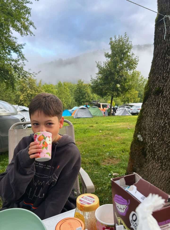 boy drinking while having breakfast outside on the camp ground in Camp Danica near Lake Bohinj