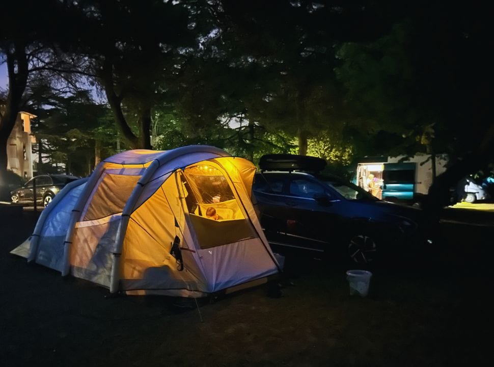 tent set in a campsite in Slovenia, lights illuminate the darkness 
