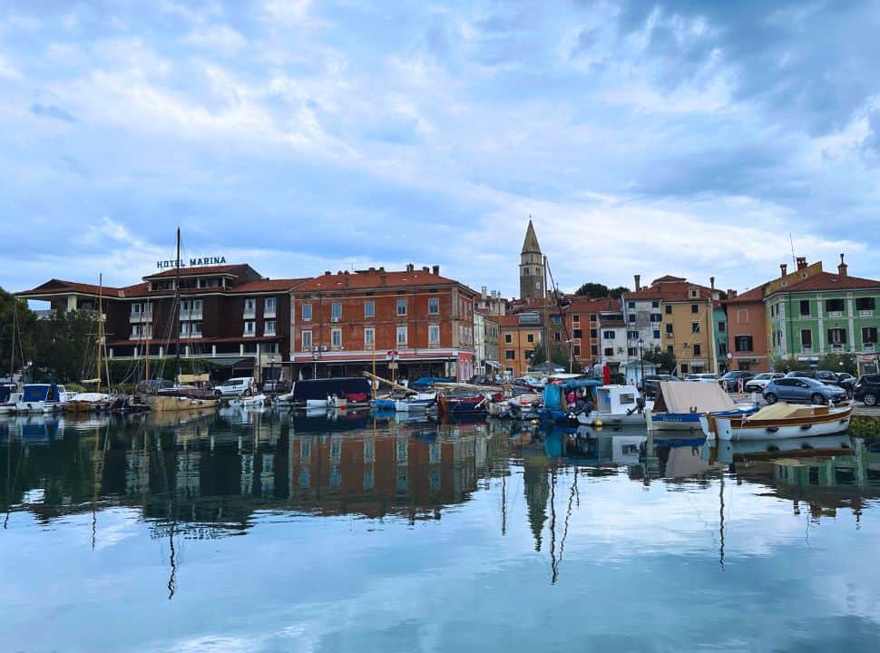 colorful houses along the harbor at a small coastal village in Slovenia, houses are reflected in the calm water