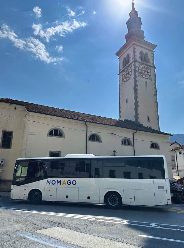 Touring car or shuttle bus waiting for passenger at its busstop located near a church in Kobarid, an inexpensive way to visit Slovenia