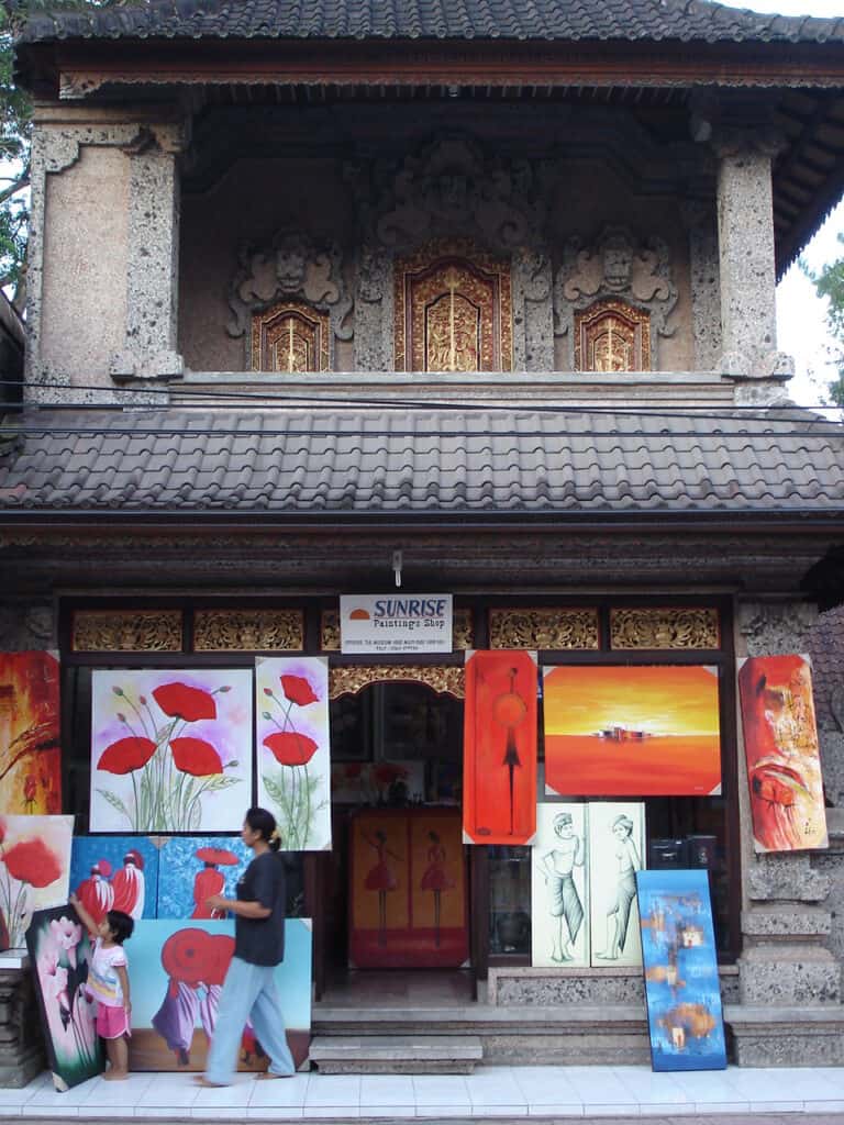 balinese styled building selling various types of paintings displayed outside along the pavement of the street in Bali