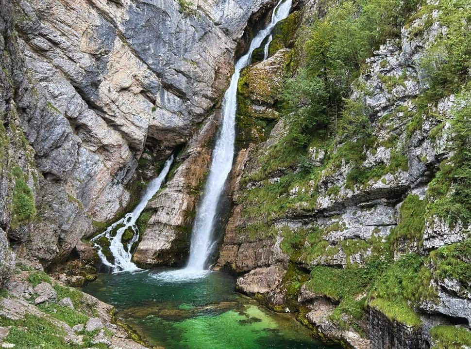 waterfall rushing down the rocks into a emerald green crystal clear pool, savica waterfall Slovenia near lake Bohinj
