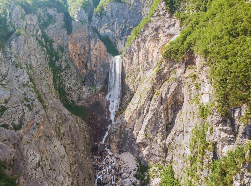 view of the Boka waterfall crashing down into the river gorge in Slovenia