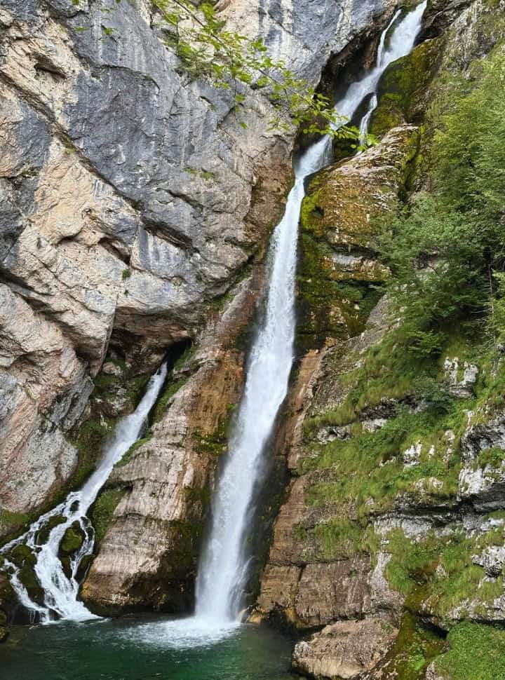 beautiful waterfall with white water crashing down into a green pool, Savica Waterfall Slovenia
