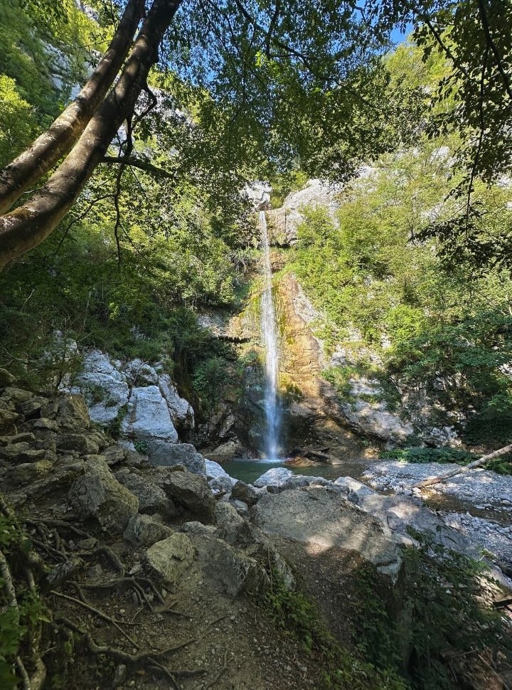 waterfall set in a lush vegetation surrounded by rocks, the sun is shining right on the water making it look even more beautiful, Slap beri Slovenia waterfall
