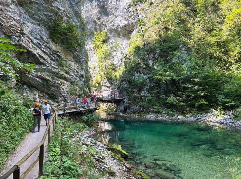 walkway going through a tall gorge and along jade green calm crystal clear water with trees along the river banks at Vintgar Gorge Slovenia