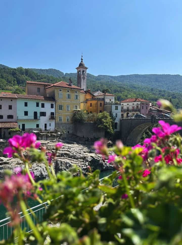 view of colourful old buildings and church built along the river gorge at Kanal Slovenia