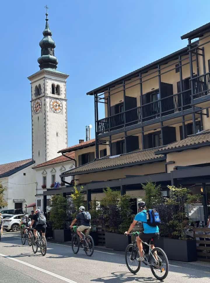 cyclists cycling along the buildings and church at kobarid Slovenia