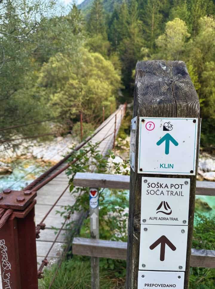 sign indicating the soča trail, pointing the way across a bridge into the forest near Bovec Slovenia