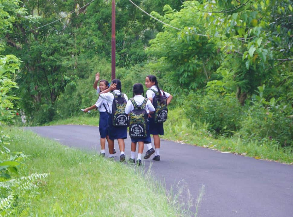 local school girls in Sidemen walking along the small street, one girl is waving hello
