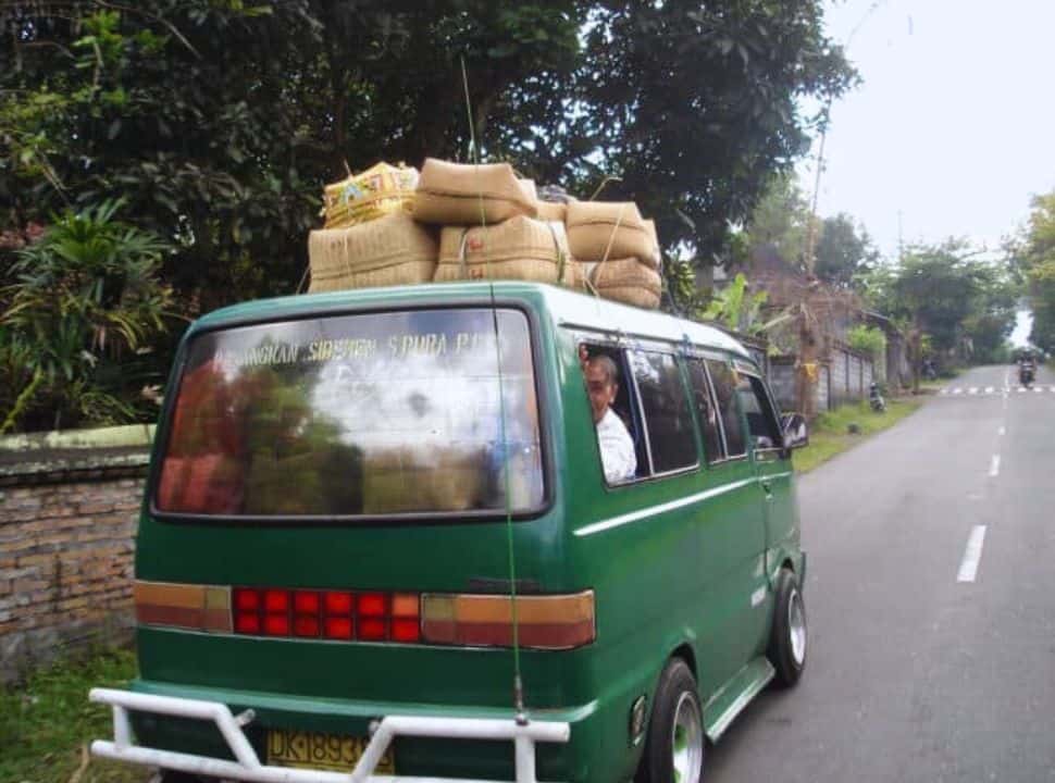 woman looking out of the window of a bemo, a public van heading for Besakih. The van is packed with baskets with offerings, which are also placed on top