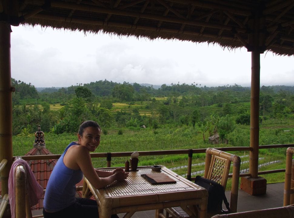 woman sitting at a table of a restaurant with first class view of rice fields and agricultural land in Sidemen Bali