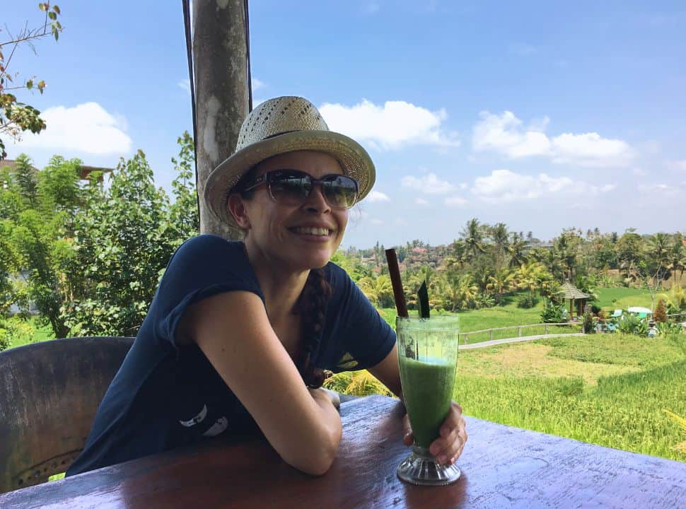 woman enjoying a green juice at a restaurant located in the rice fields in Ubud Bali