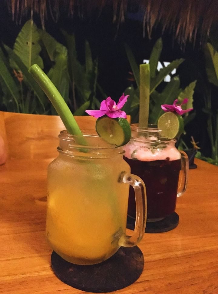 juices decorated with a slice of lime and a flower, the straw is green and natural from a plant