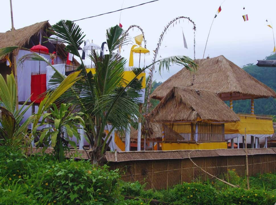 temple complex beautifully decorated with yellow and white cloth, colorful umbrellas and penjor, a long arching decorated bamboo pole