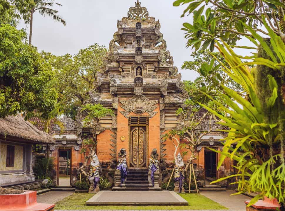 traditional Balinese structured gate at the Ubud palace with statues, a beautiful decorated door set in a green garden courtyard