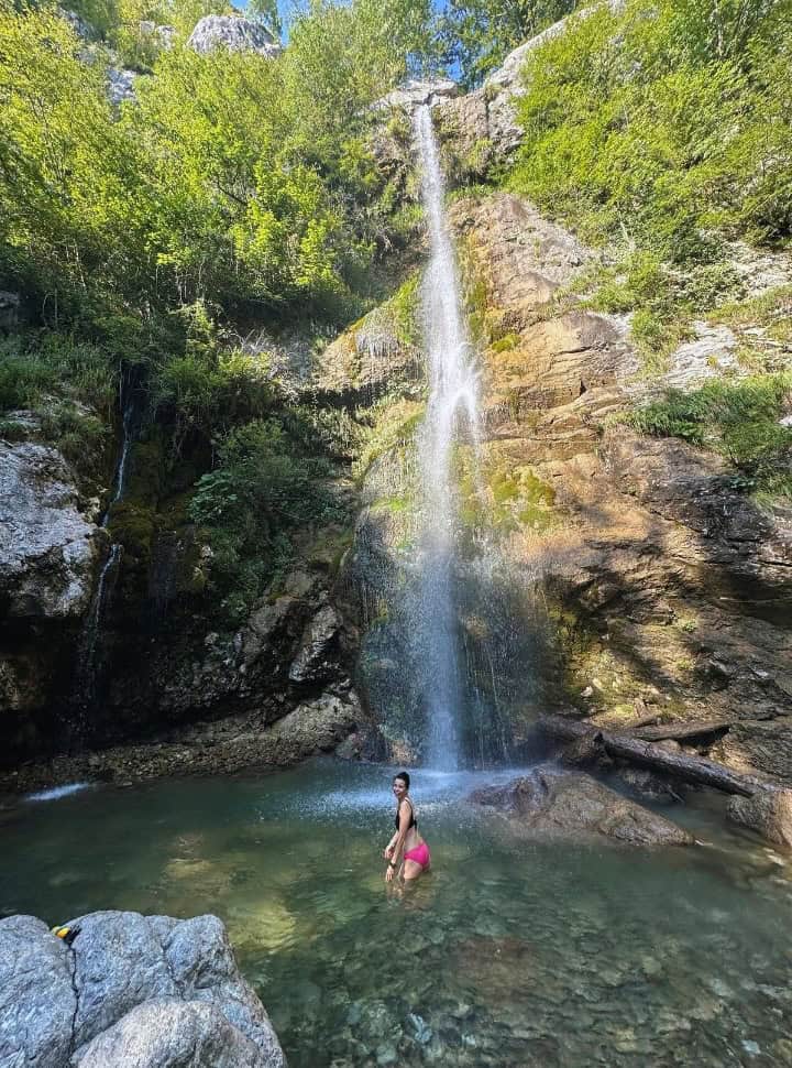 woman standing in the pool of water at the bottom of the waterfall of Beri, Slovenia. 