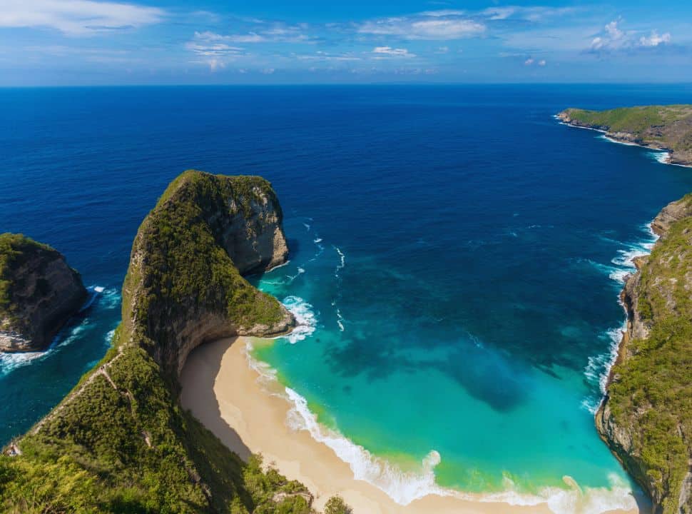 cliff beach with stunning soft sanded white beach and emerald green and ocean blue water on Nusa Penida island near Bali