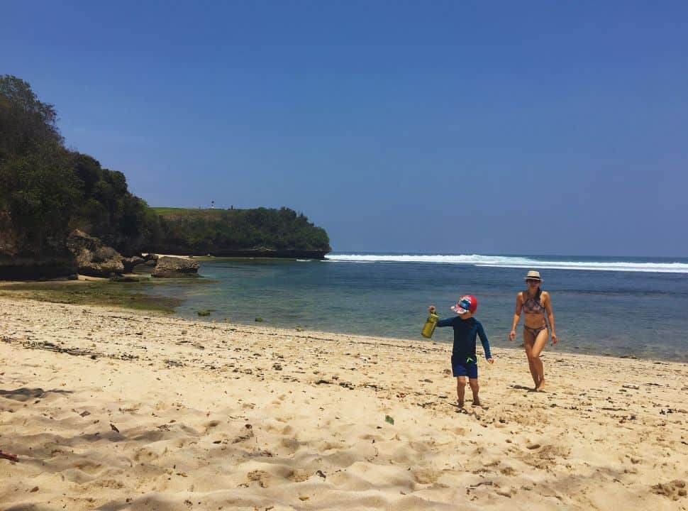 mother and son walking from the water up the beach with soft sand at Balangan beach Bali