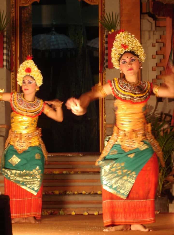 two Balinese woman dressed in beautiful traditional Balinese clothing and head dress dancing on stage in Ubud