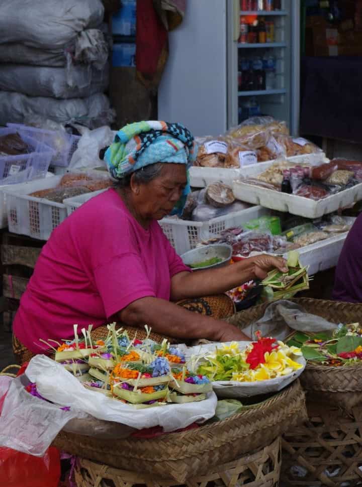 woman at the ubud market selling flowers and pre-made offerings at Ubud Market