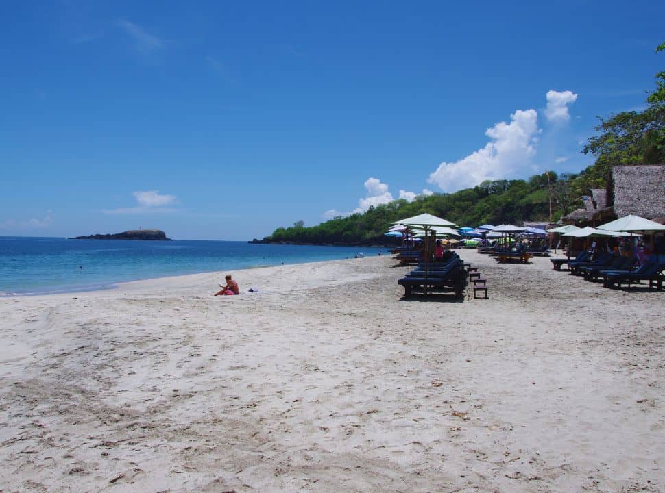 white sanded beach with stunning blue water in the east of Bali, there are sun chairs with umbrellas for rent