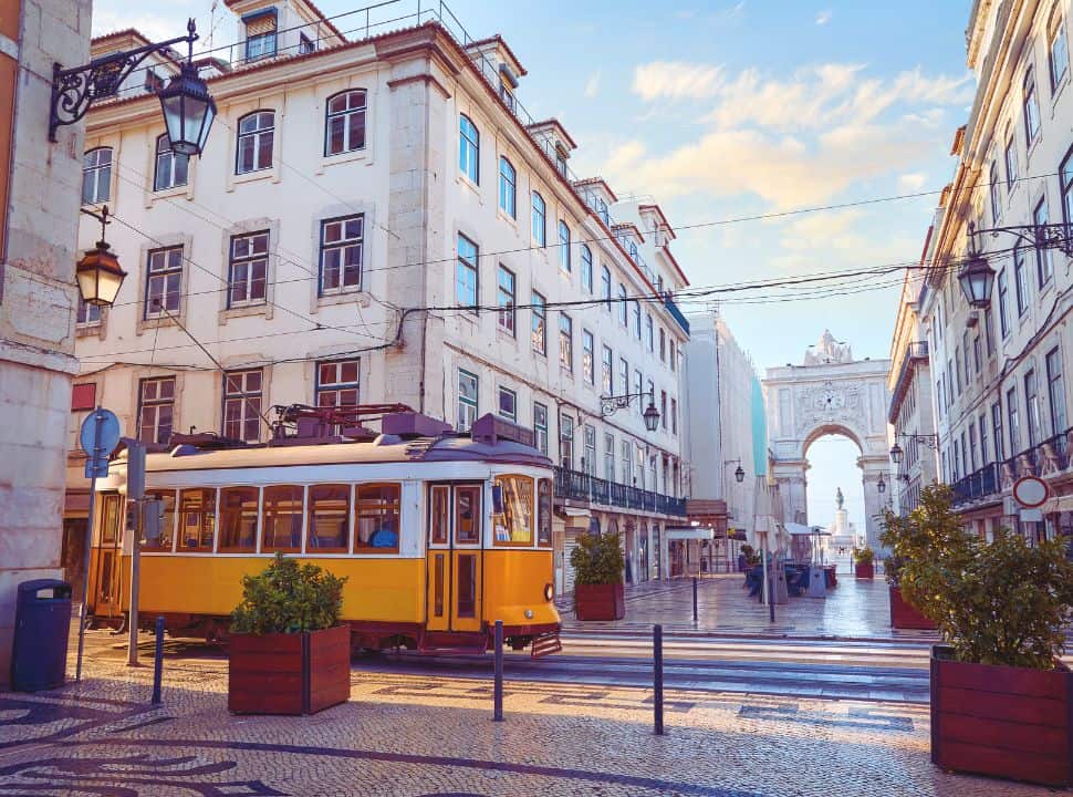 tram passing city center of Lisbon with the clock entrance a triumphal arch in Praça do Comércio