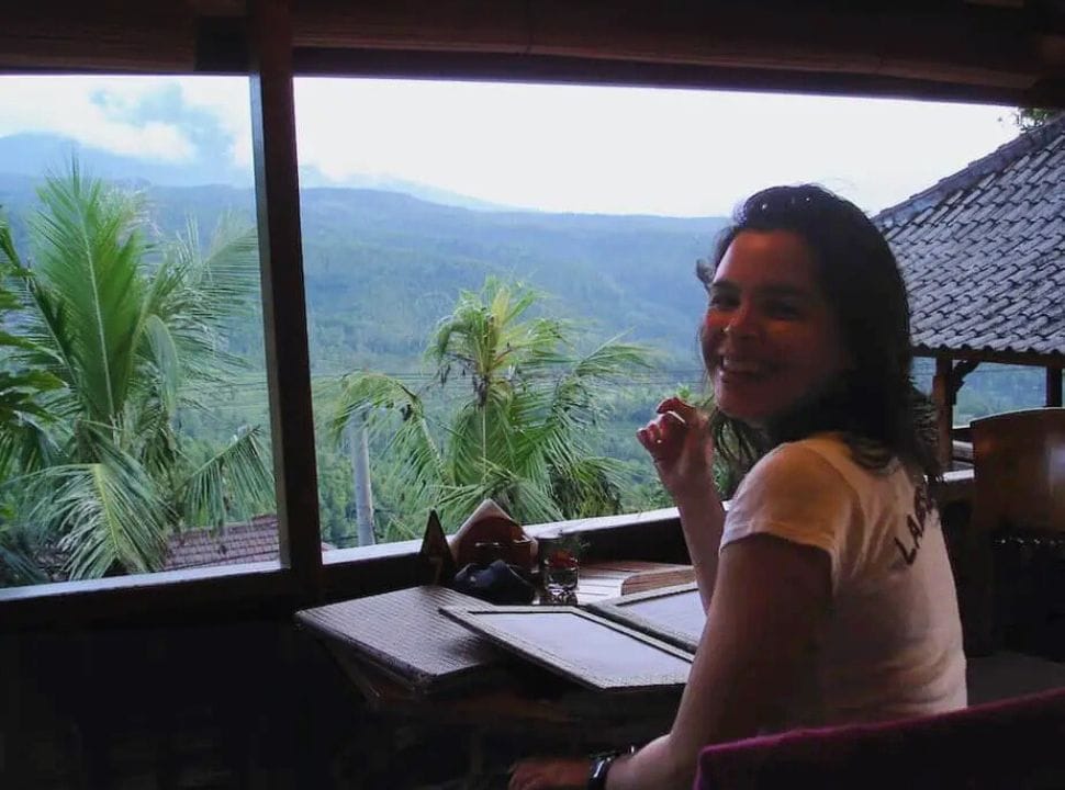 woman sitting at a restaurant with a menu with a view over a green valley in Munduk Bali