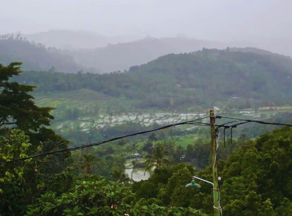 view of a rice field valley with heavy rainy clouds above in Munduk Bali