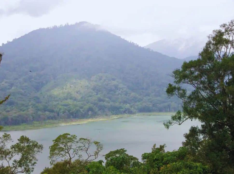 view from the hills of a lake surrounded by mountains in mist weather conditions in Bali