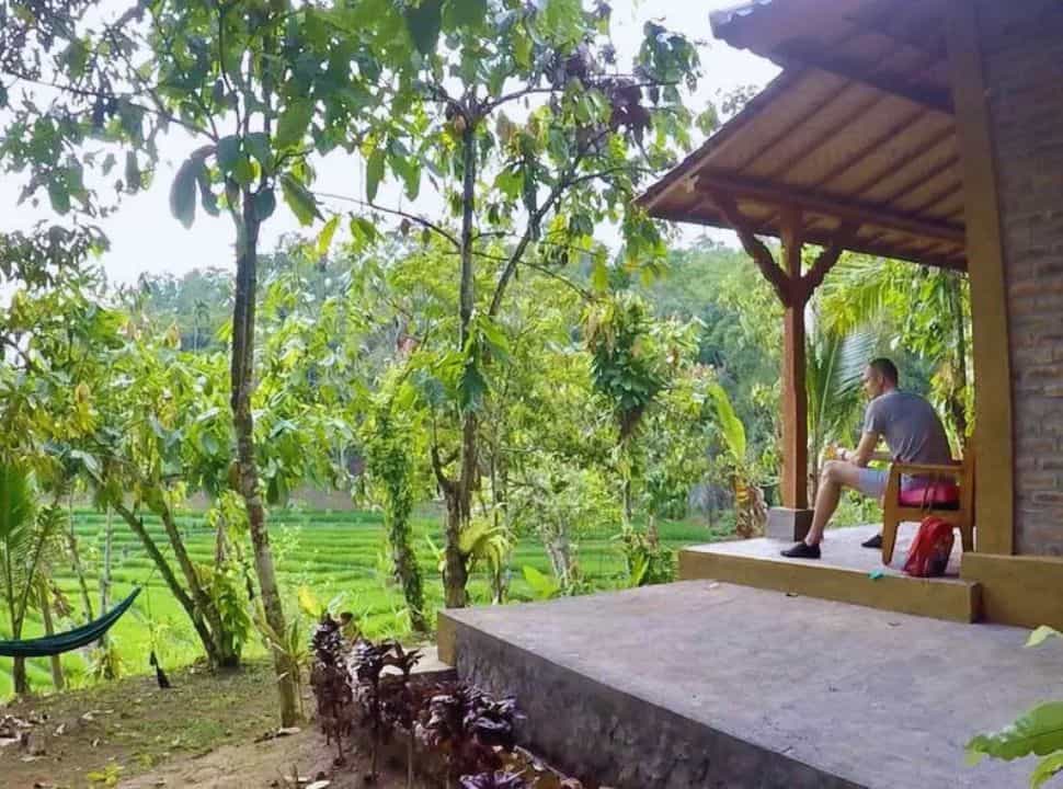 man sitting on the verandah at one of the bungalows at the Sari Devi Ecolodge