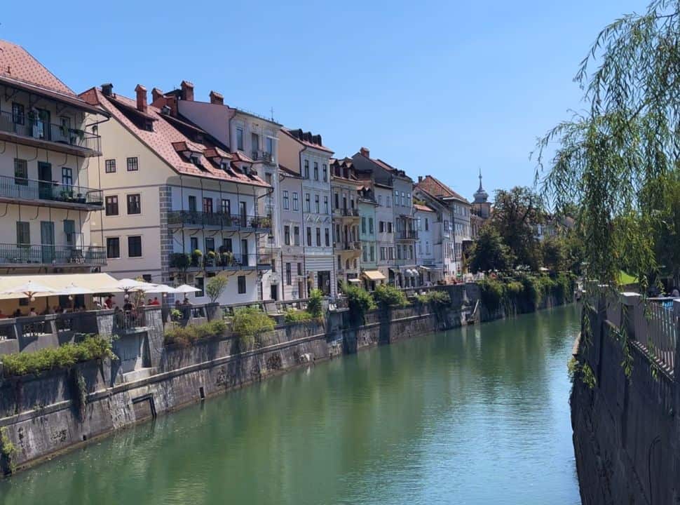Ljubljana river side with tall characterful colored houses and restaurant terraces