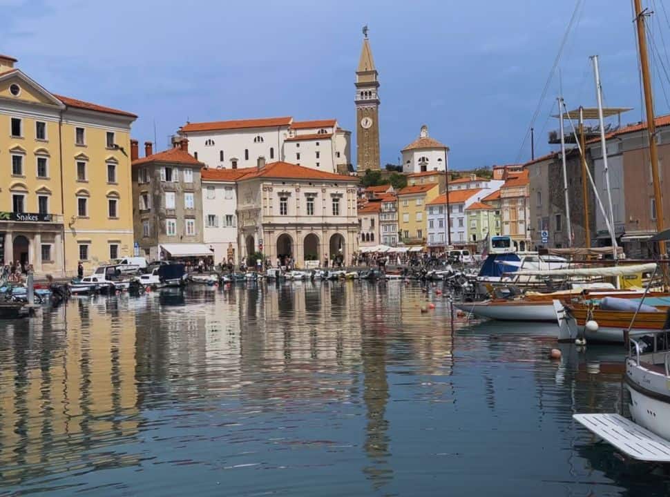 harbour of Piran Slovenia surrounded by charming old buildings in various colors, a clocktower is visible between the rooftops