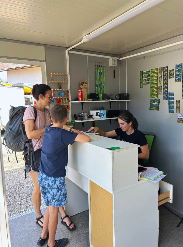 mother and son standing at a counter of a kayak tour company in Slovenia while the lady behind the counter arranges the payment 