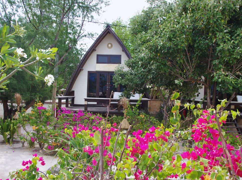 small beach accommodation surrounded by trees and flowers in Lombok