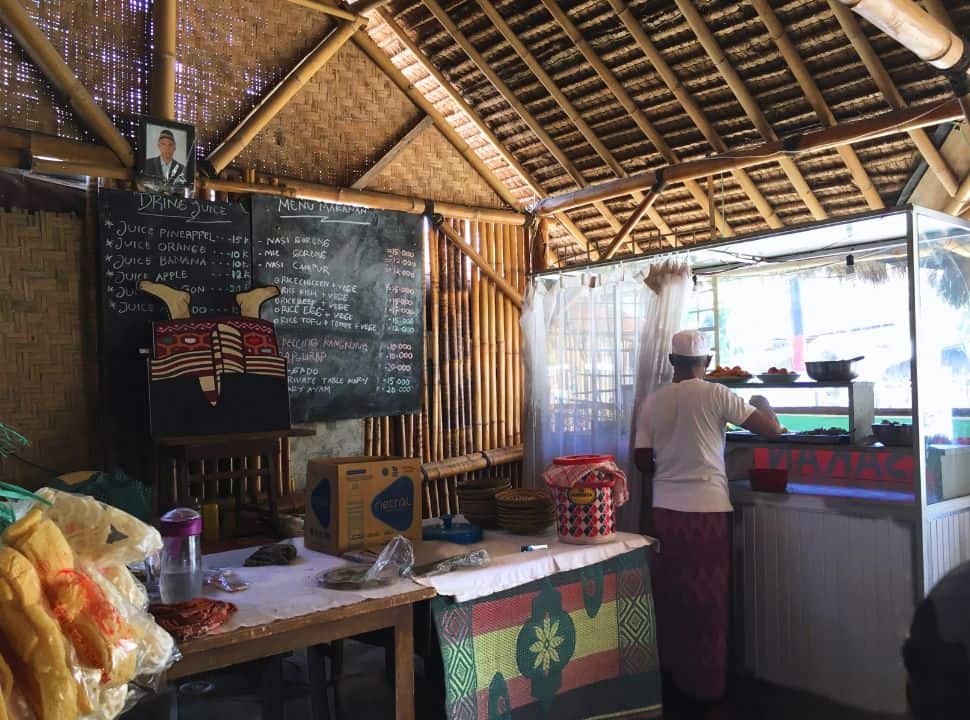 man selecting various local dishes from the display in a bamboo thatched roof and walls in Lombok island. 