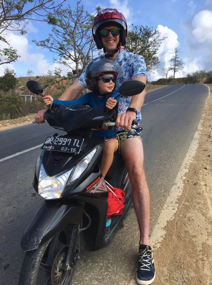 father and son standing on the side of a quiet main road on Lombok island