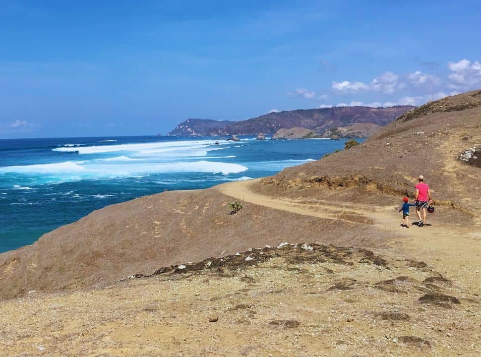 father and son walking along dry baren hills along the coastline of south Lombok