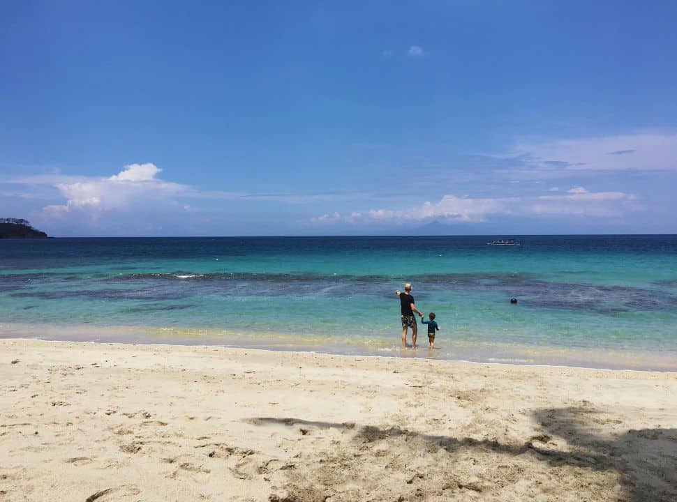 father and son walking towards the crystal clear water at Nipah beach