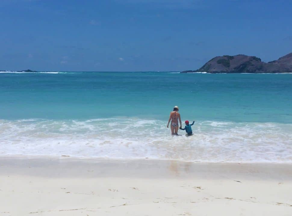 Mother and son walking into the beautiful blue ocean water at Tanjung Aan, a white sanded beach in Lombok