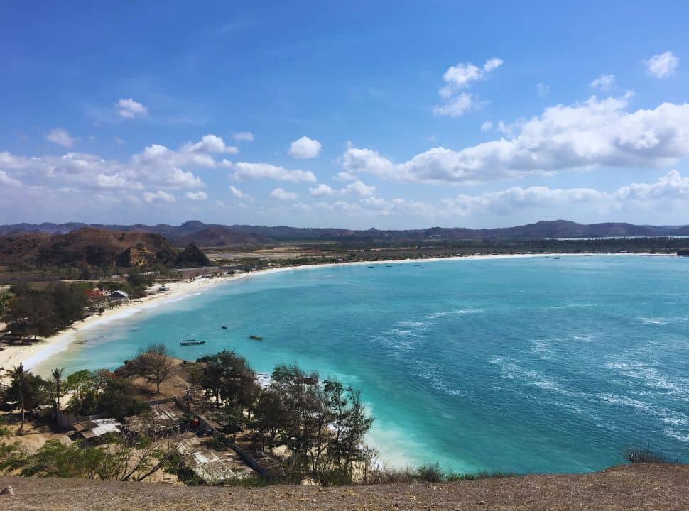 view of the whole stretch of Tanjung Aan bay, the dry arid land, white sand beach strip and the blue turquoise water