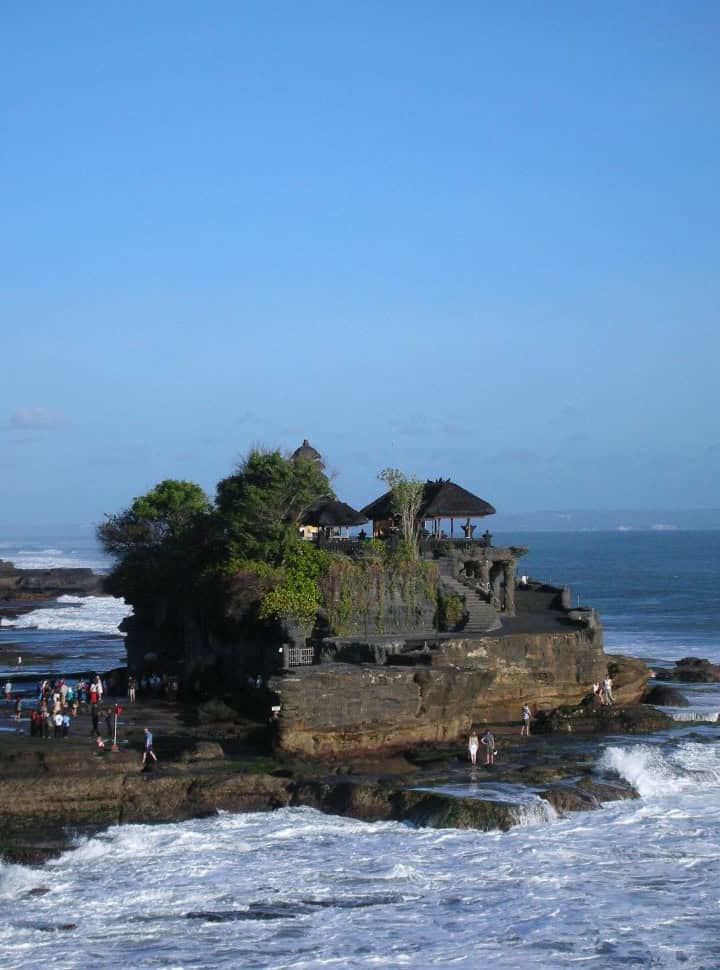 Balinese temple set in the ocean with tourist walking around it in South Kuta Bali