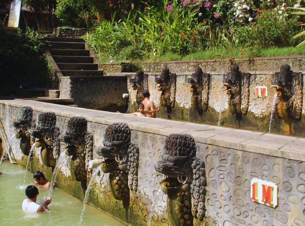 people soaking in the hotsprings made from stone and decorated with statues at Banjar Hotsprings North Bali